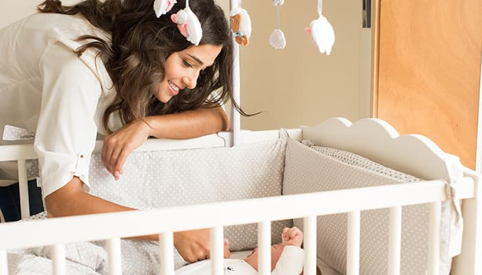 Mother putting baby to sleep in a crib